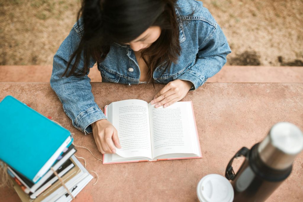 a woman in blue denim jacket reading a book