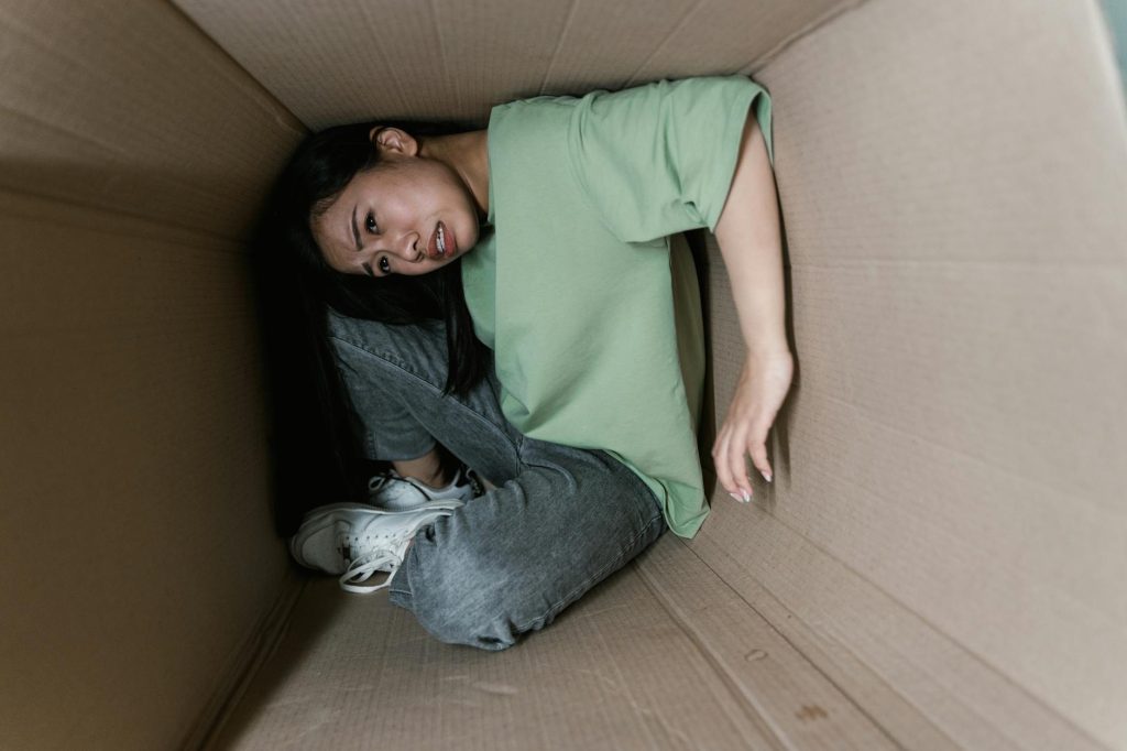 a fearful woman having claustrophobia in a cardboard box
