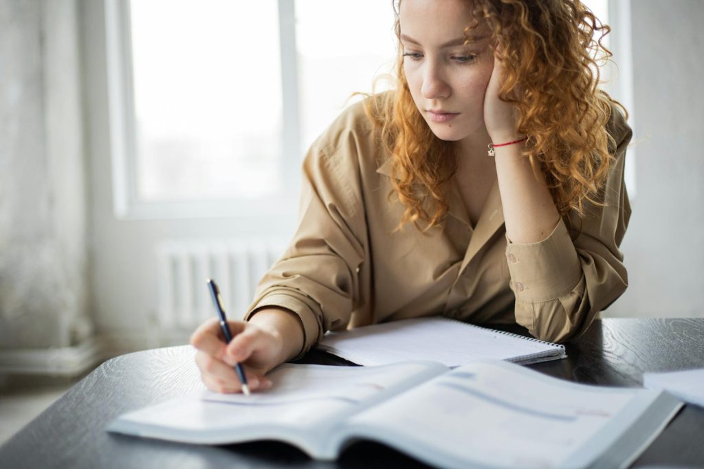 crop clever woman writing in book